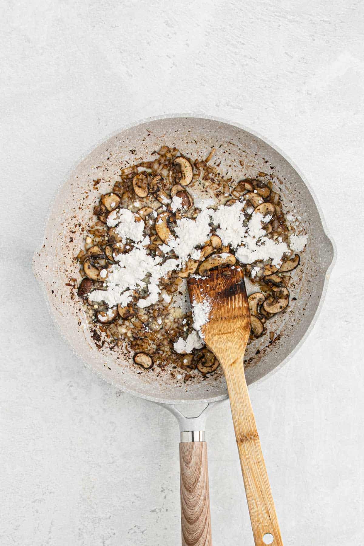 Sautéed onions and sliced mushrooms sprinkled with flour in a skillet
