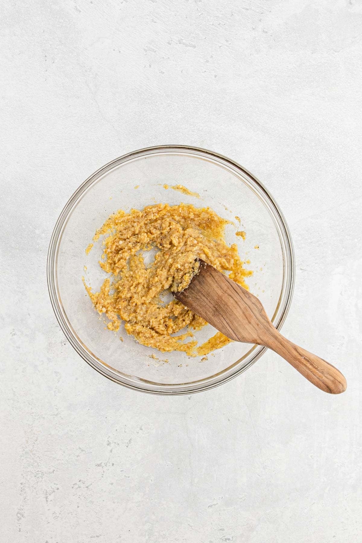 Breadcrumb, egg, garlic, and seasoning mixture combined into a paste in a glass bowl