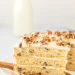 A slice of butter pecan cake being removed on a white background