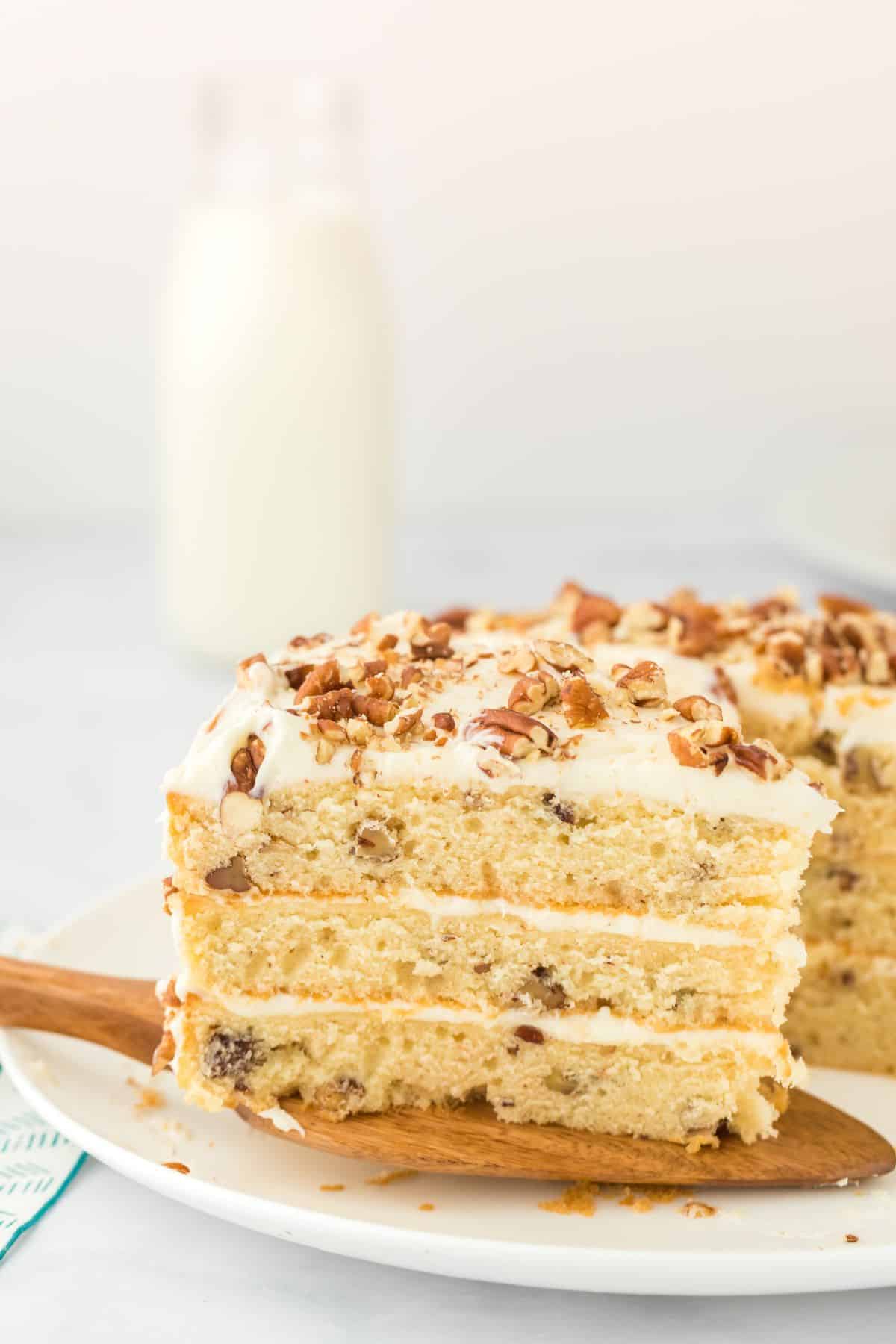 Slice of butter pecan cake on a wooden cake server