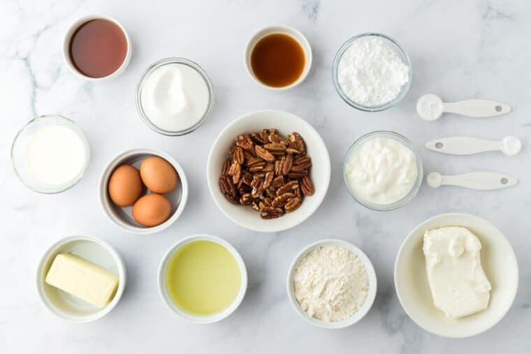 Cake ingredients in white bowls on white background