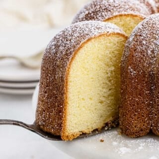 A slice of buttermilk pound cake being lifted from a whole cake