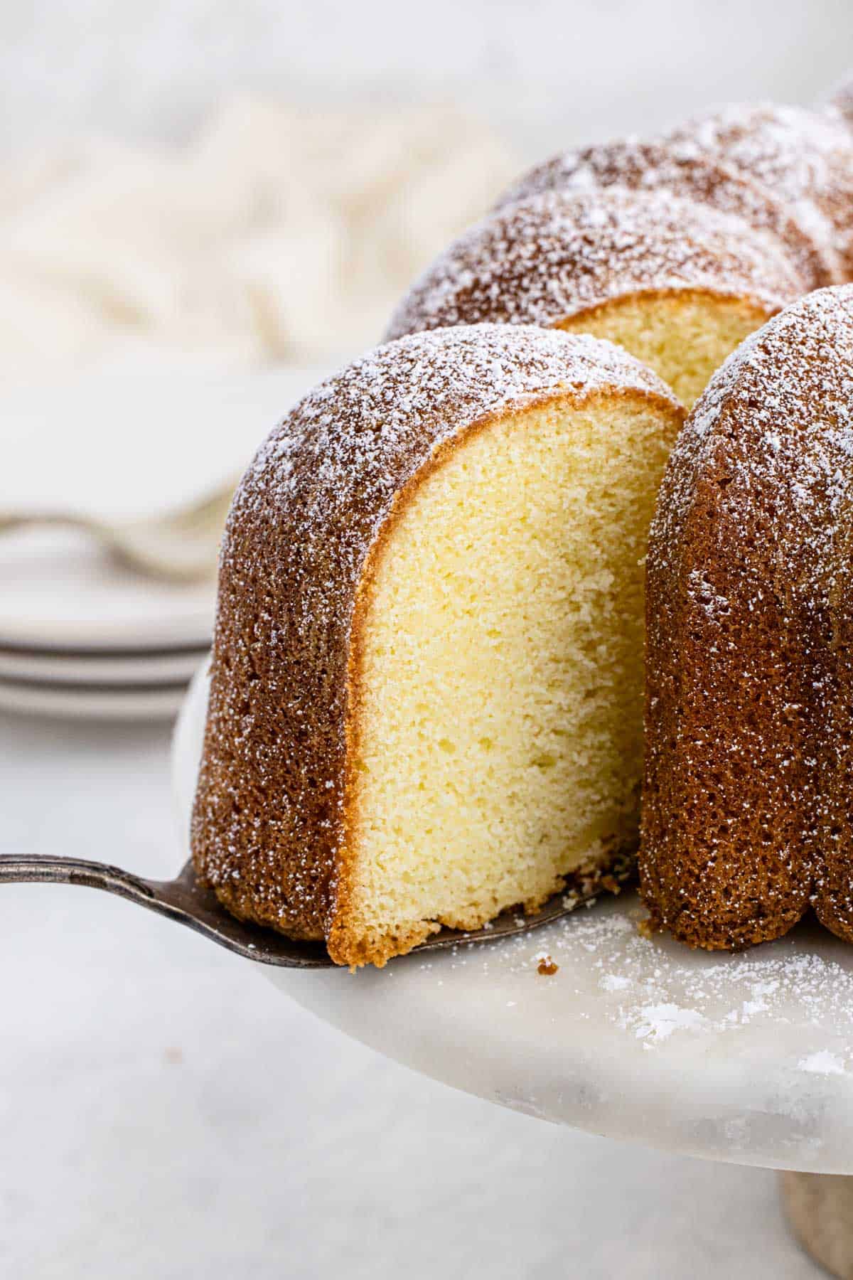 Close up of a slice of buttermilk pound cake being pulled out of the cake with a cake server
