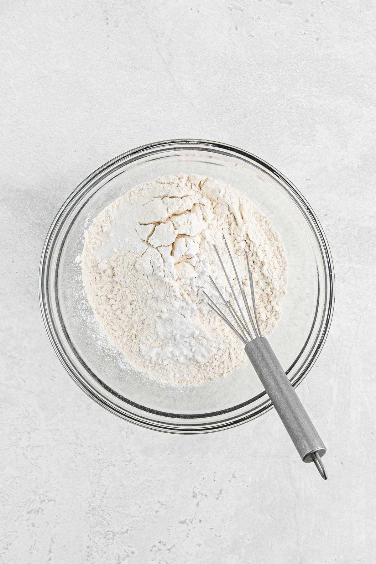 Mixing bowl with flour and a whisk resting on the edge, ready to combine dry ingredients