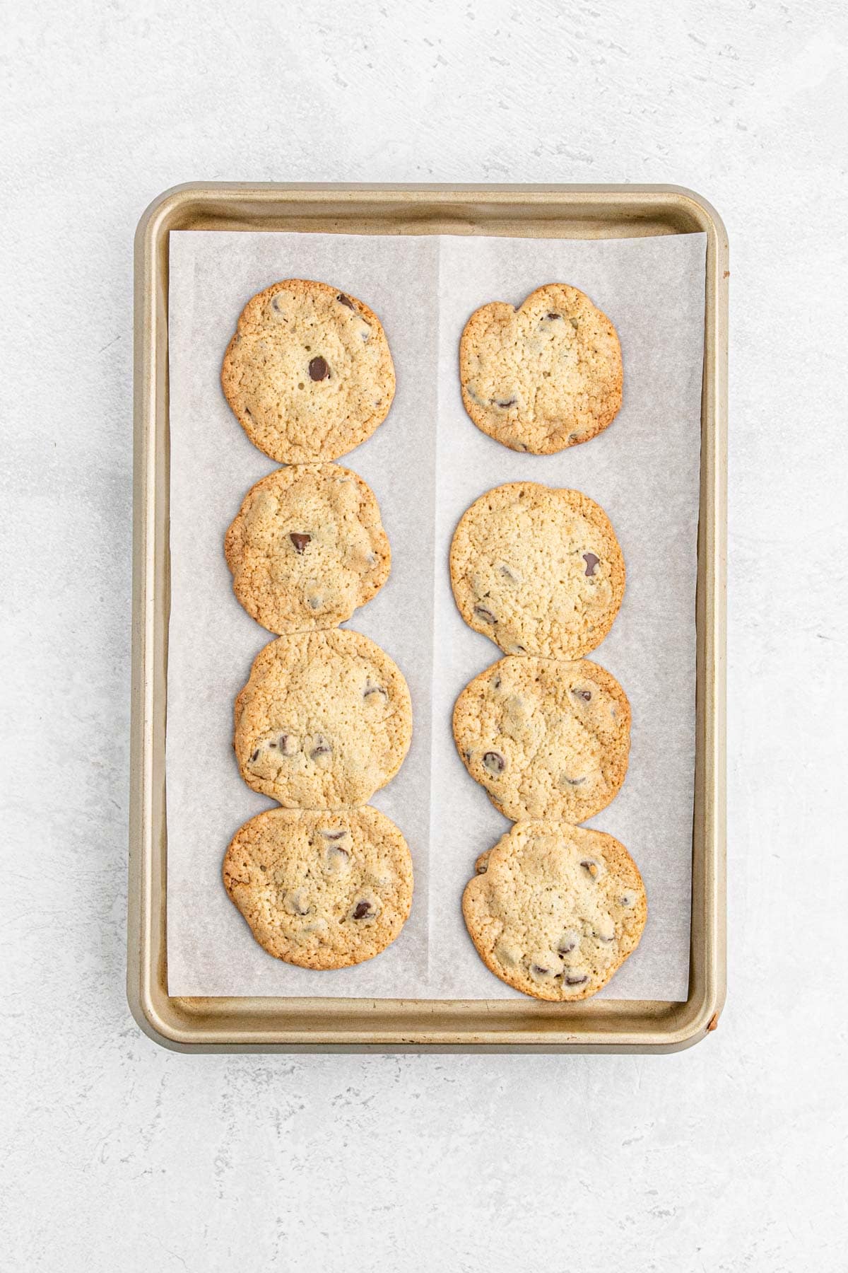 Baked chocolate chip cookies cooling on the baking sheet