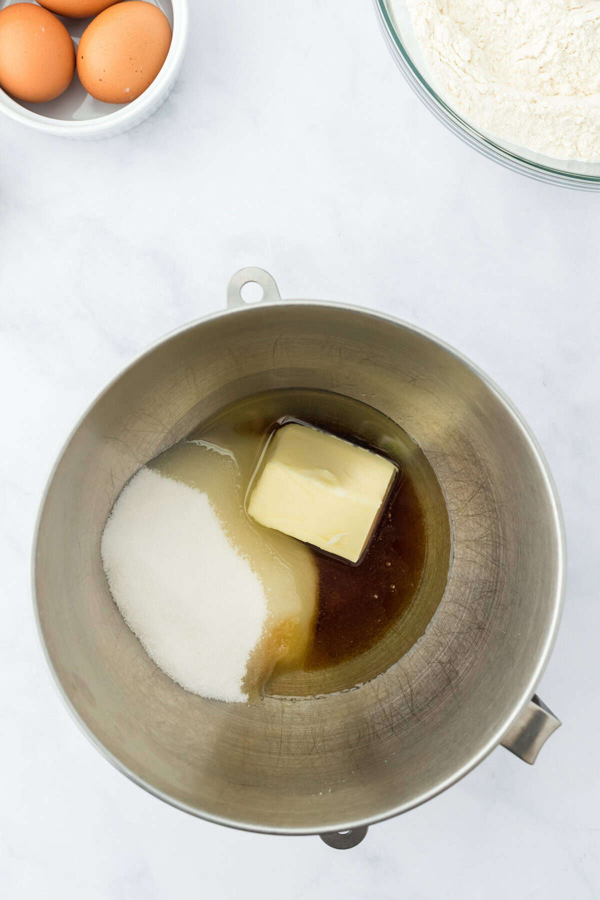 Butter, sugar, maple syrup and oil in a bowl on a white background