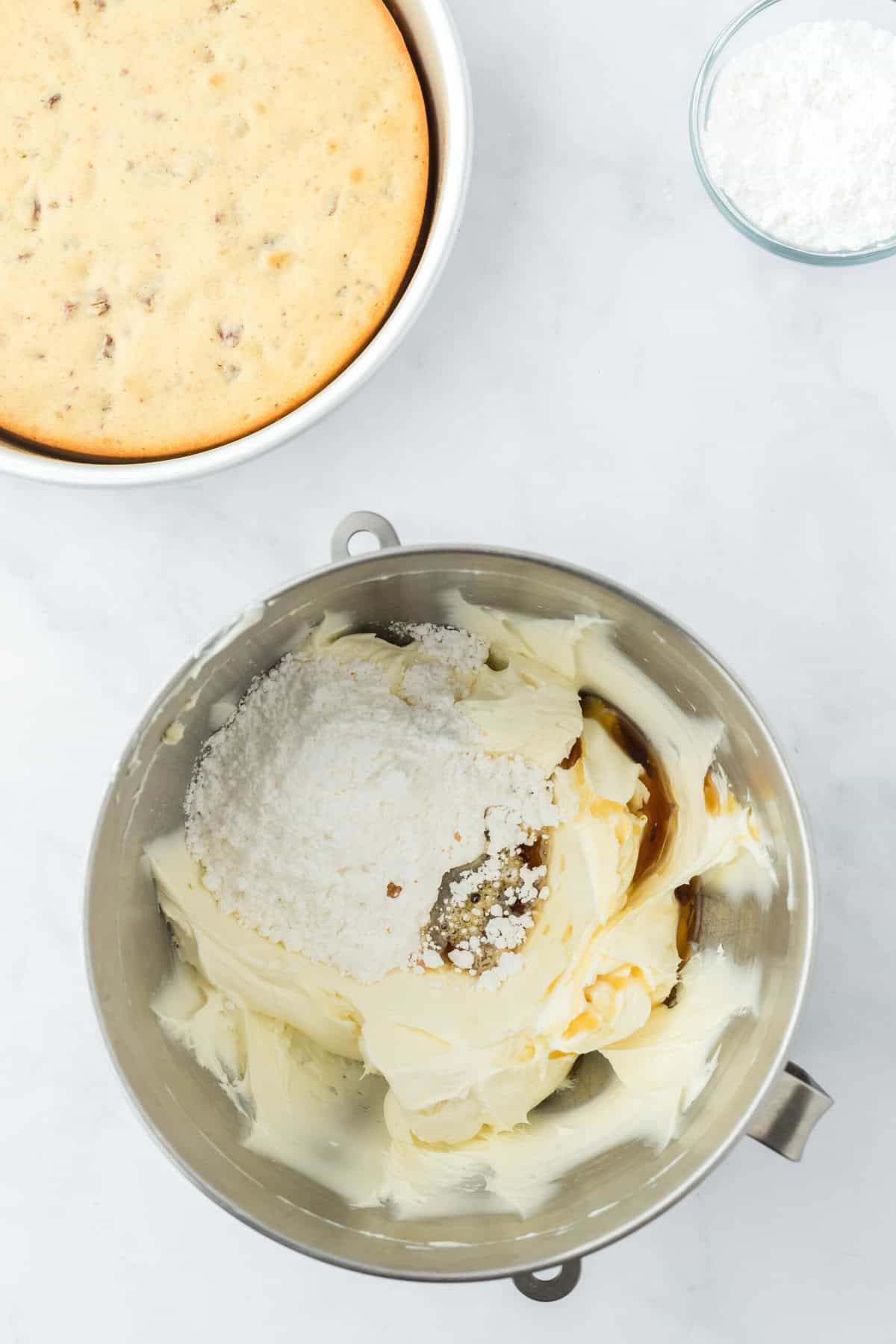 Confectioner's sugar added to a stand mixer bowl on white background