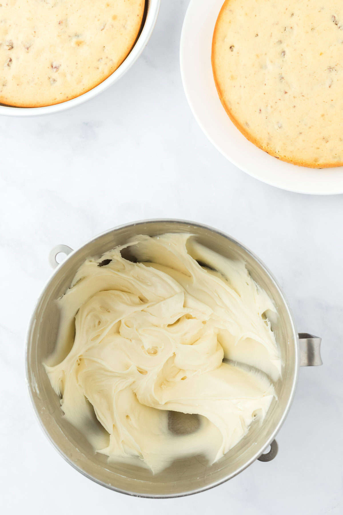 Smooth maple cream cheese frosting in a mixer bowl on white countertop