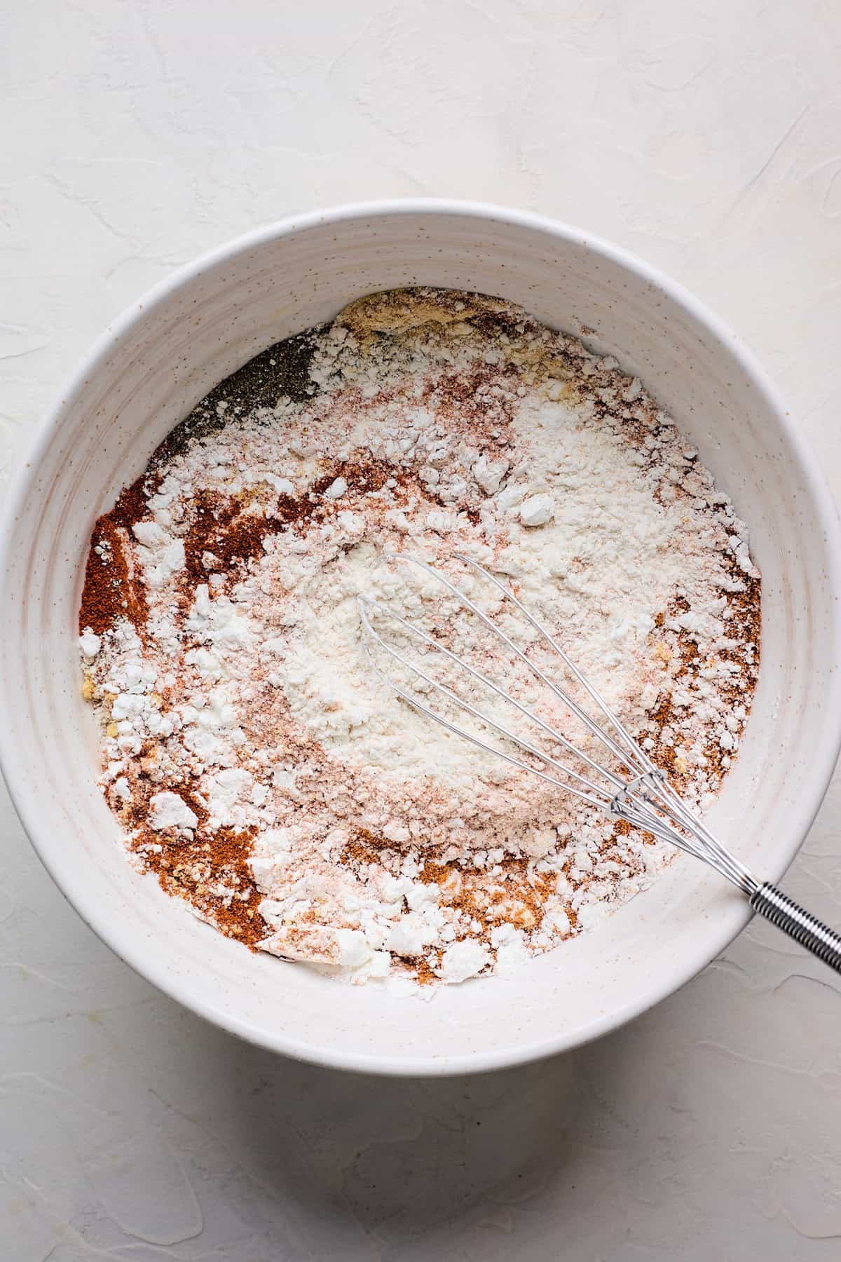 Spices whisking into flour in a white bowl