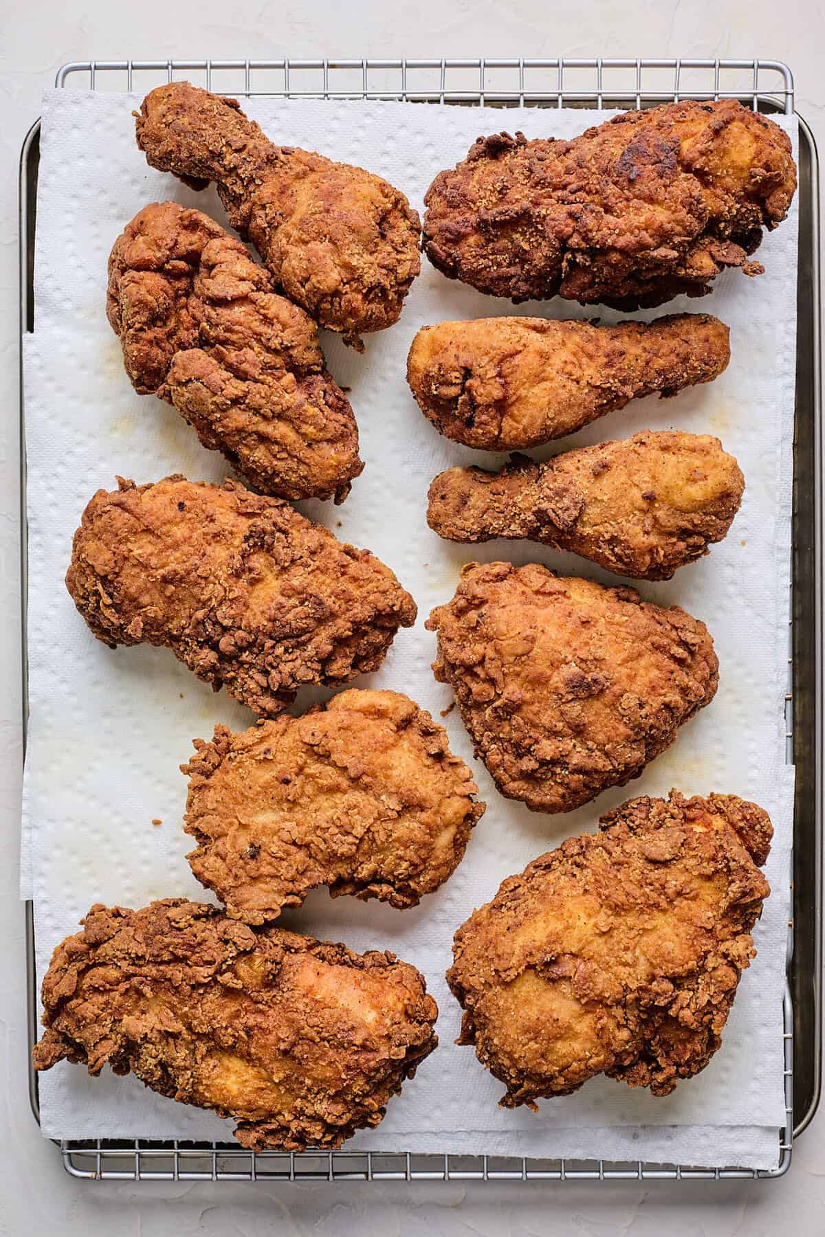 Fried chicken draining on paper towels on baking sheet