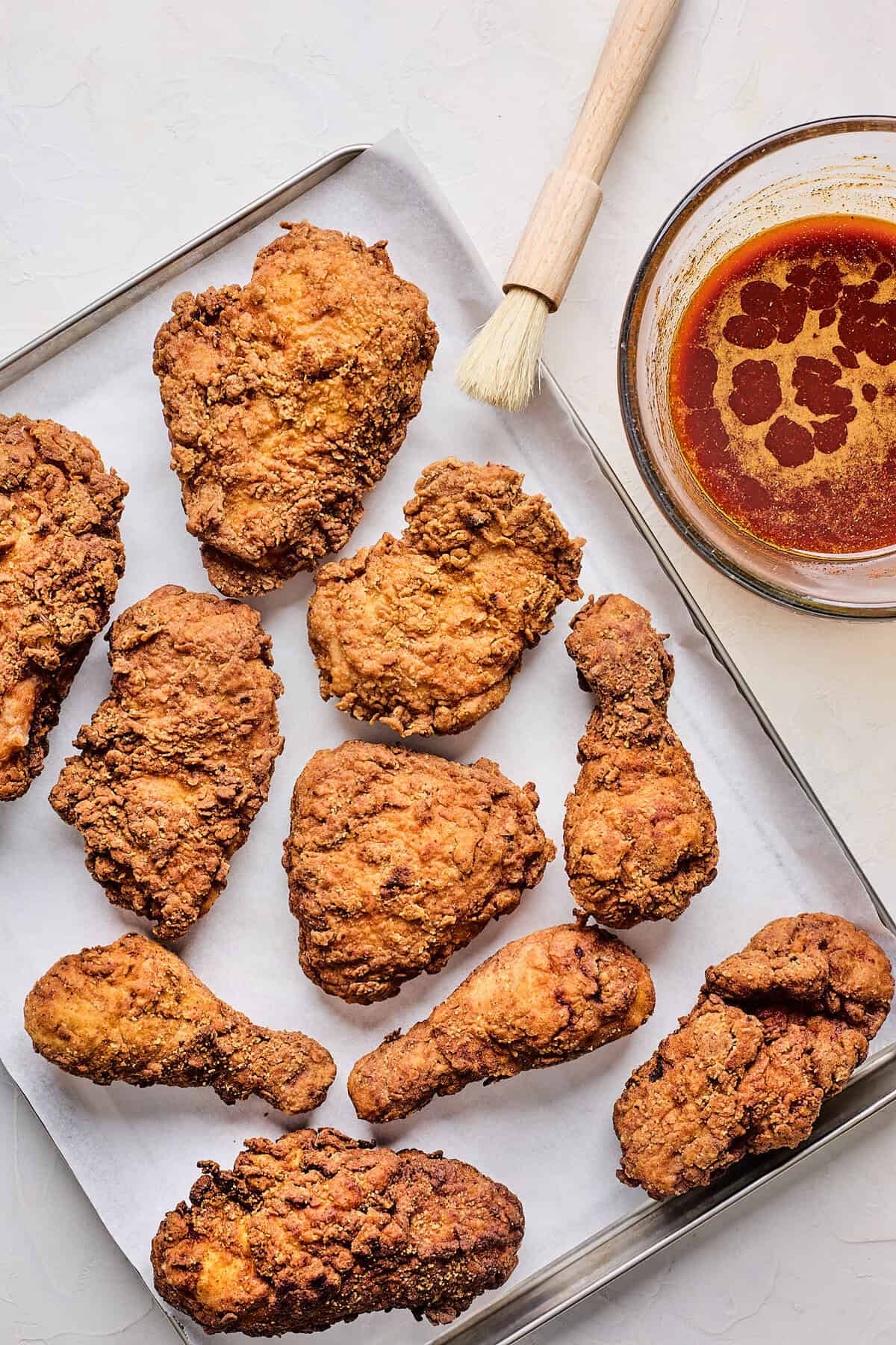 Fried chicken on a baking sheet next to hot sauce