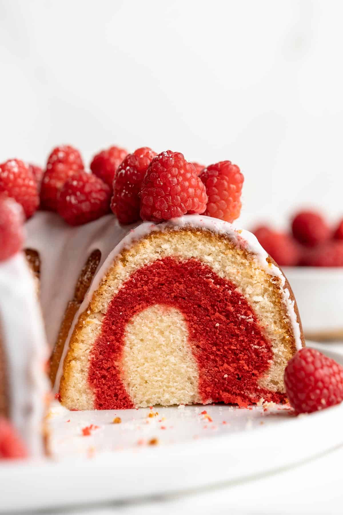 Closeup shot of a slice cut off the white chocolate raspberry bundt cake to show the inside of the cake