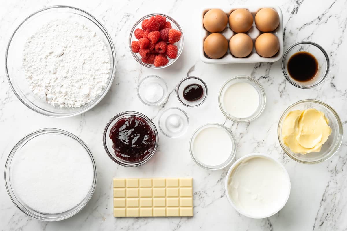 Overhead shot of ingredients to make white chocolate raspberry bundt cake on a white surface
