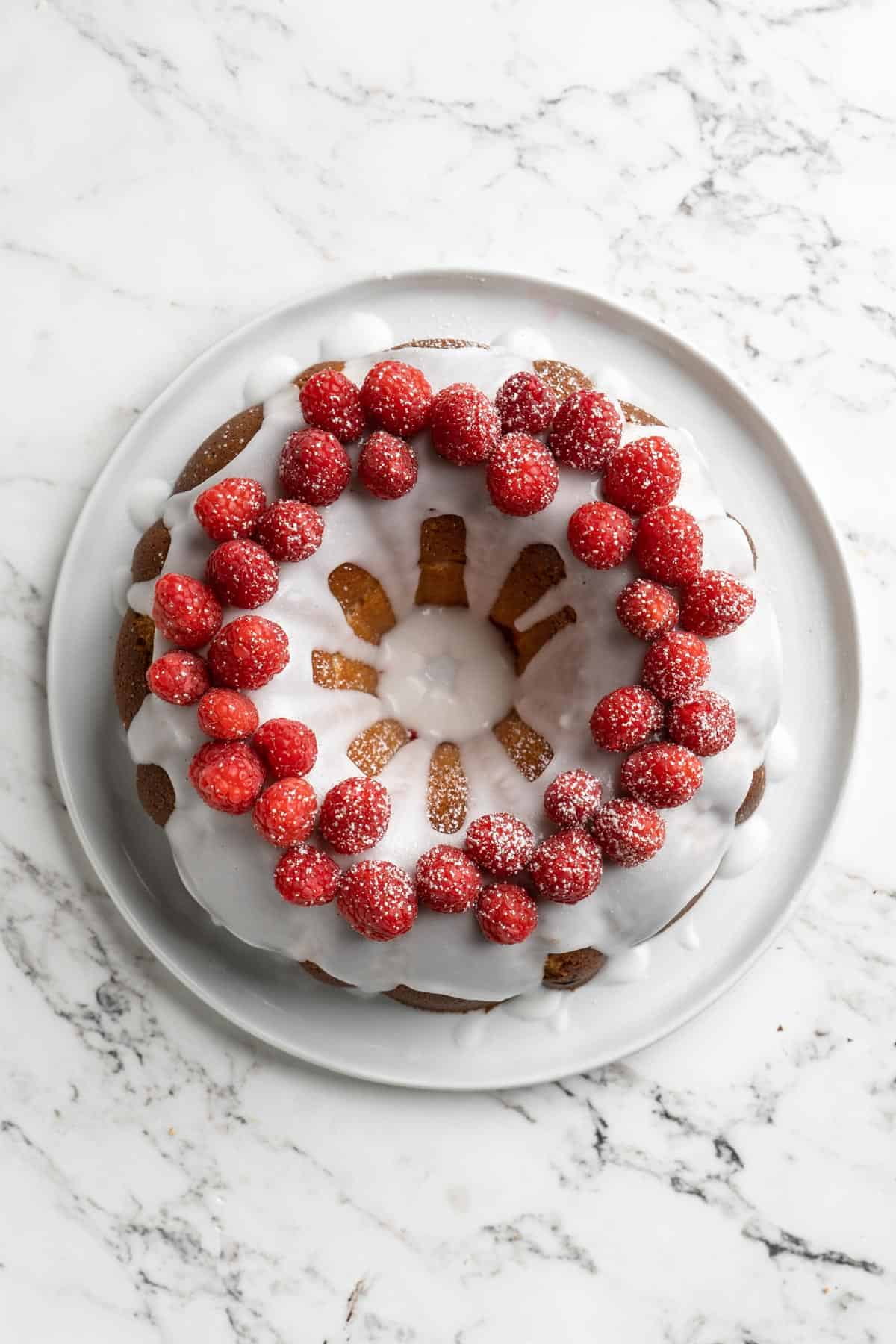Baked and garnished white chocolate raspberry bundt cake on a white plate