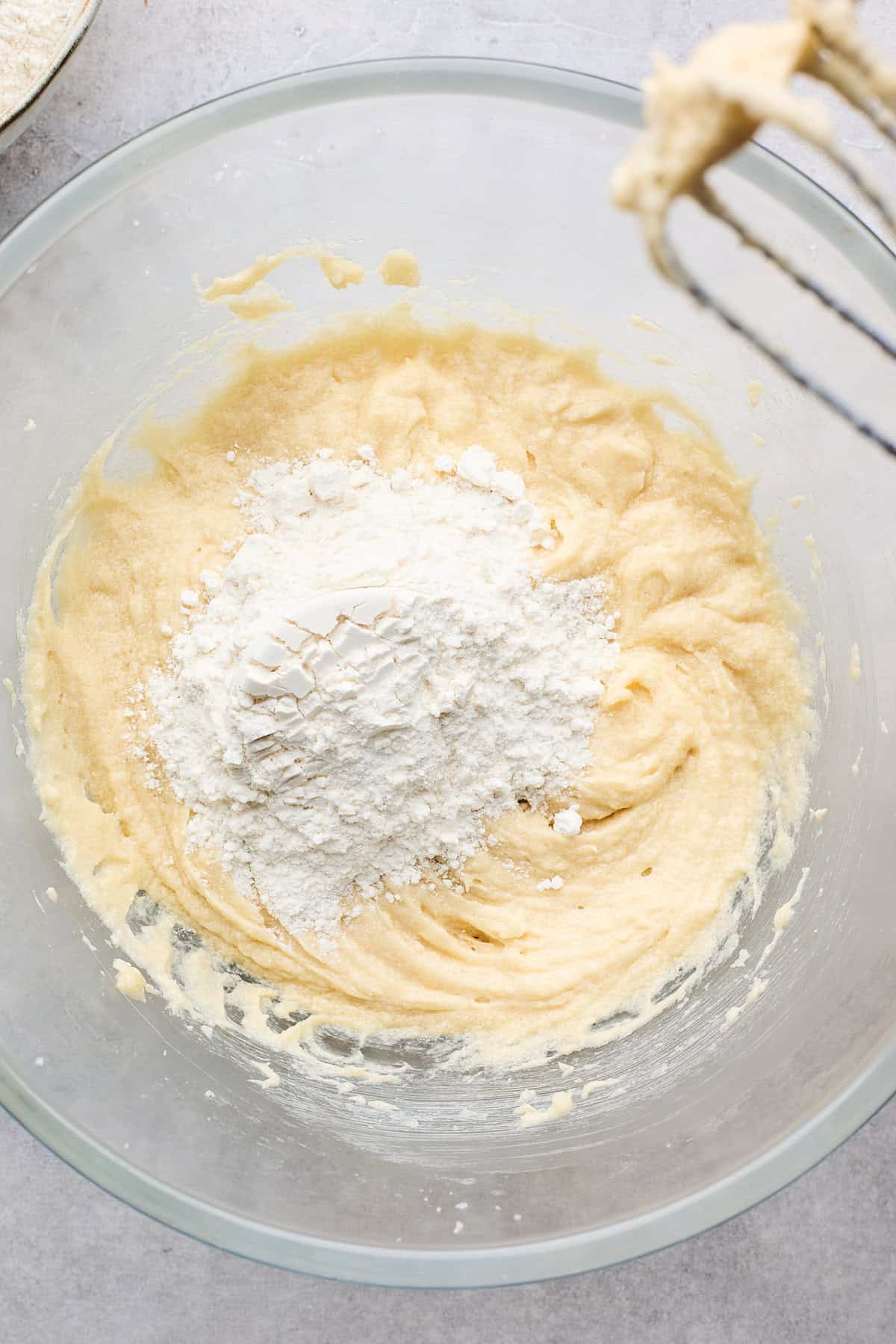 Dry ingredients added to a glass bowl before mixing with beaters nearby