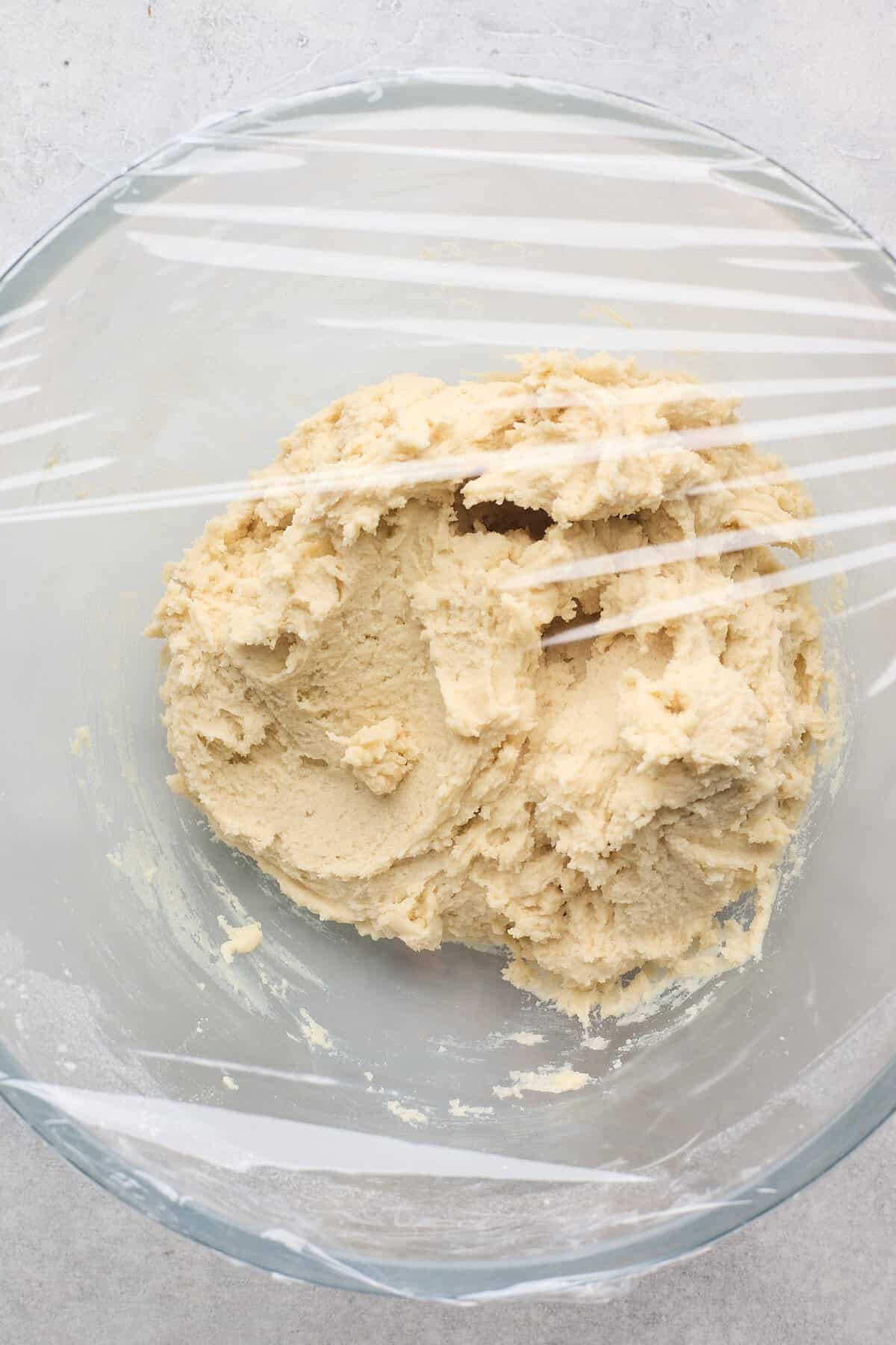 Plastic wrap placed over a bowl of old fashioned tea cake cookie dough