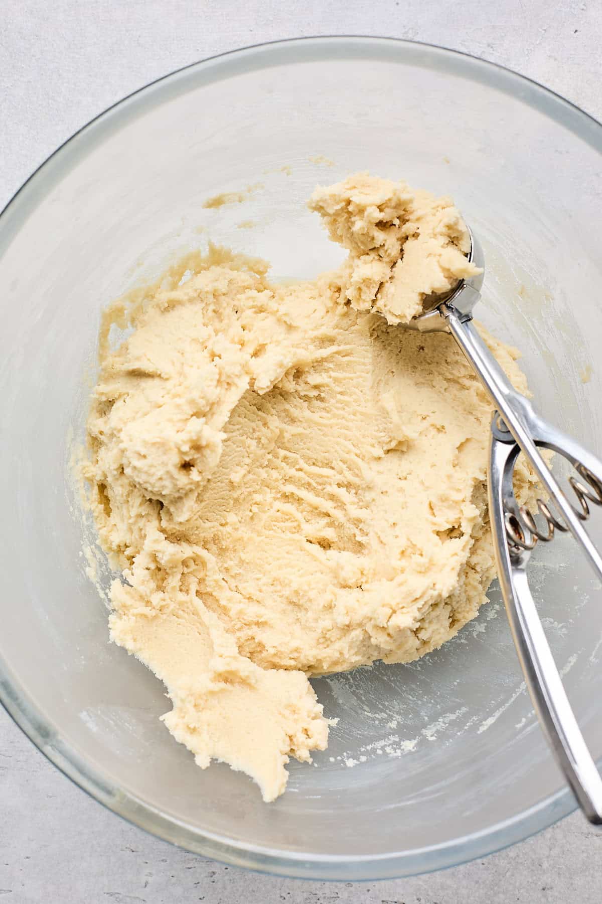 Cookie dough being scooped into balls from large bowl