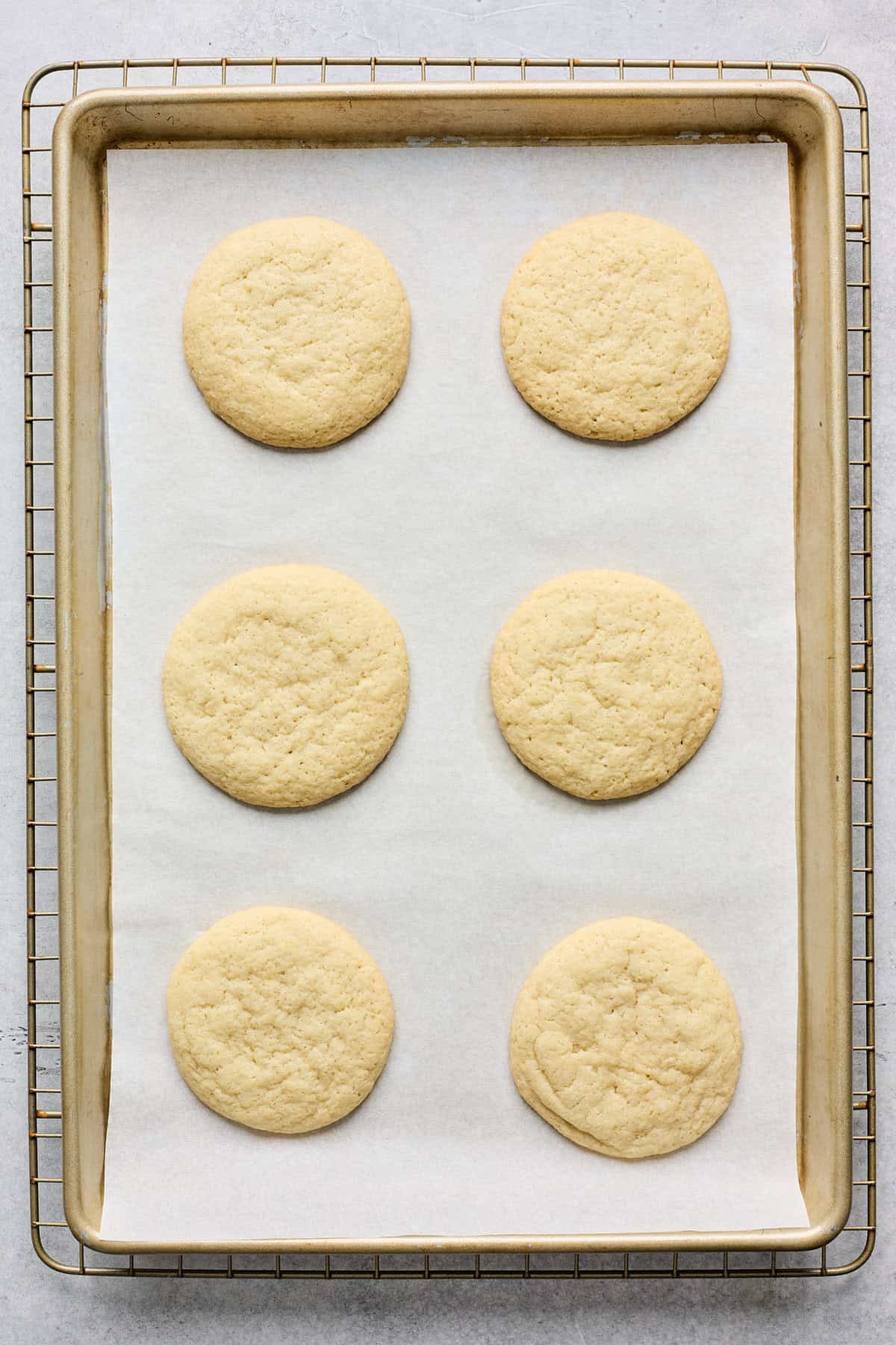 Baked tea cakes out of the oven on a baking sheet.