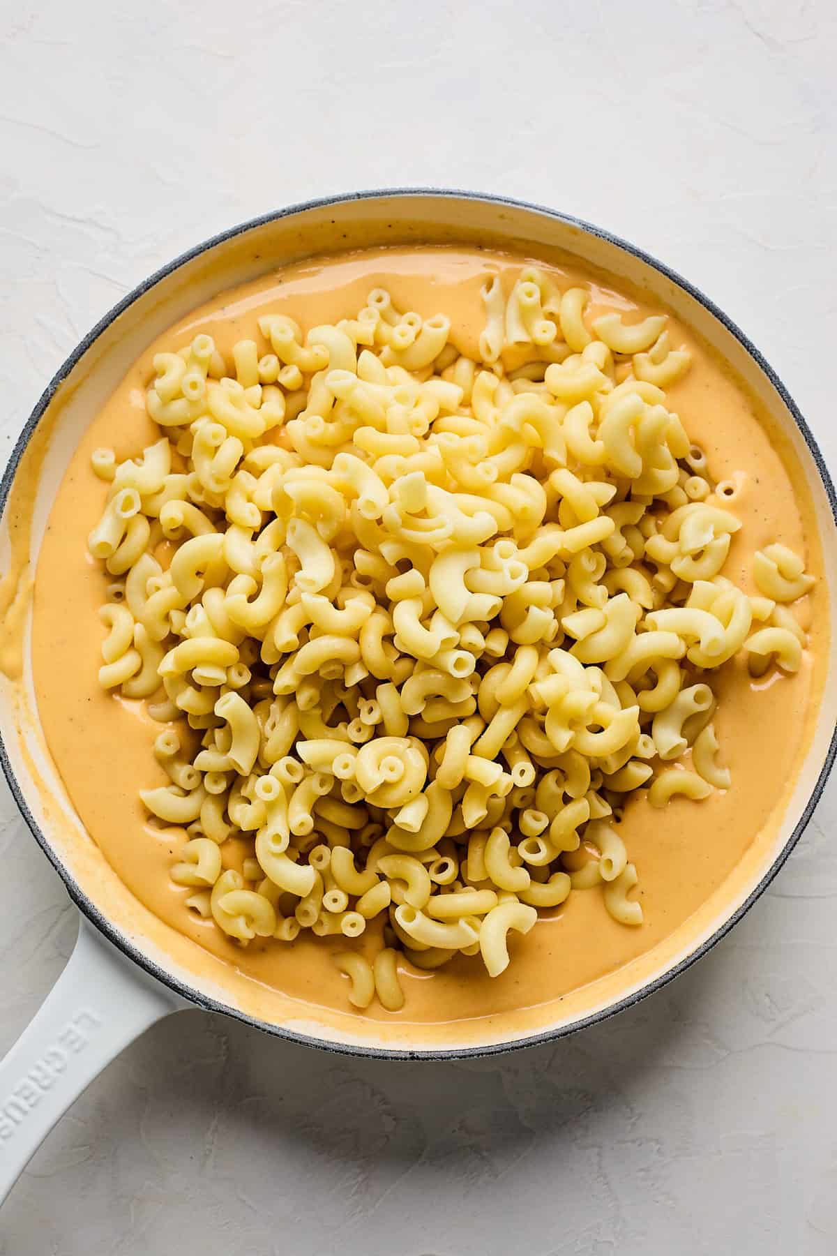 Cooked elbow pasta poured into a velveeta cheese sauce