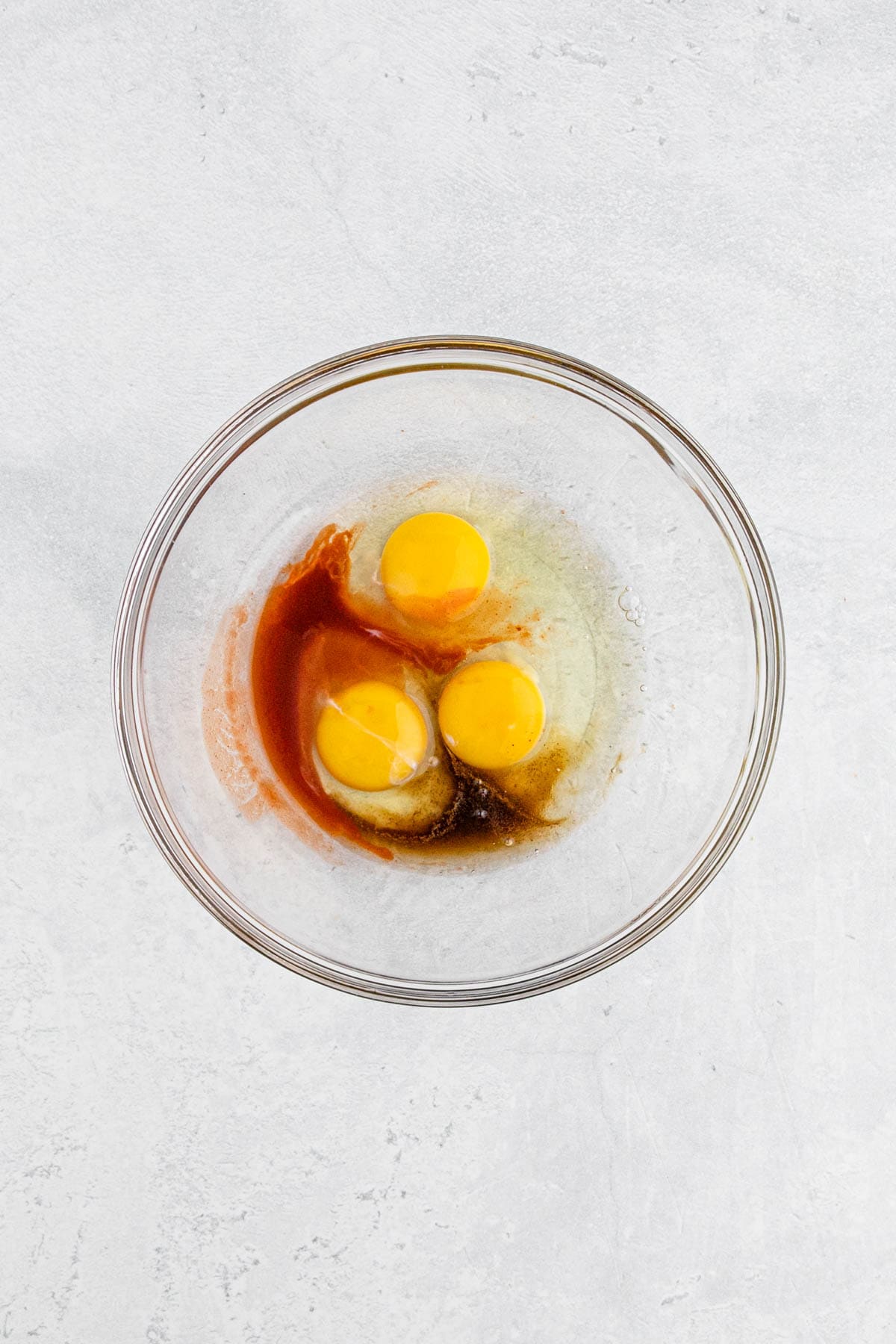Overhead view of eggs, hot sauce, and worcestershire sauce in a mixing bowl