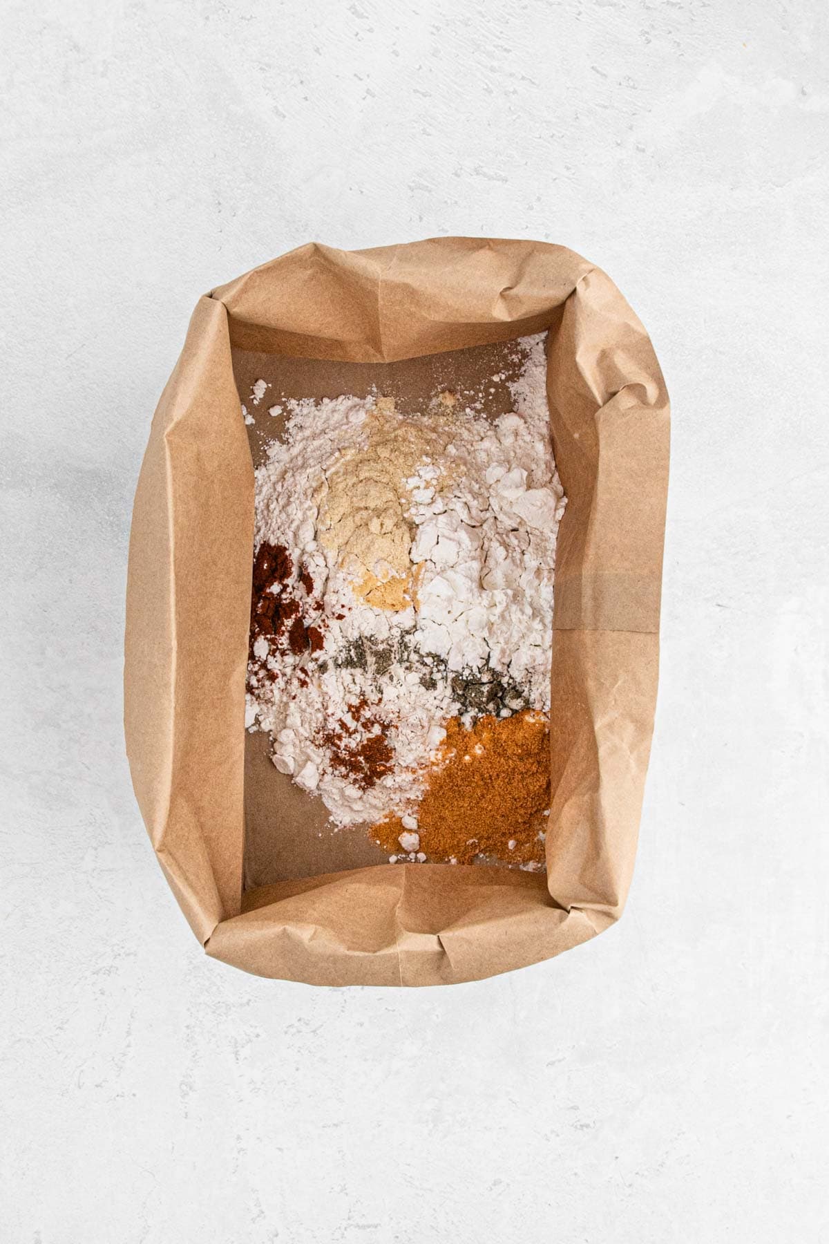 Dry mixture of flour and spices in a paper bag, ready for coating chicken