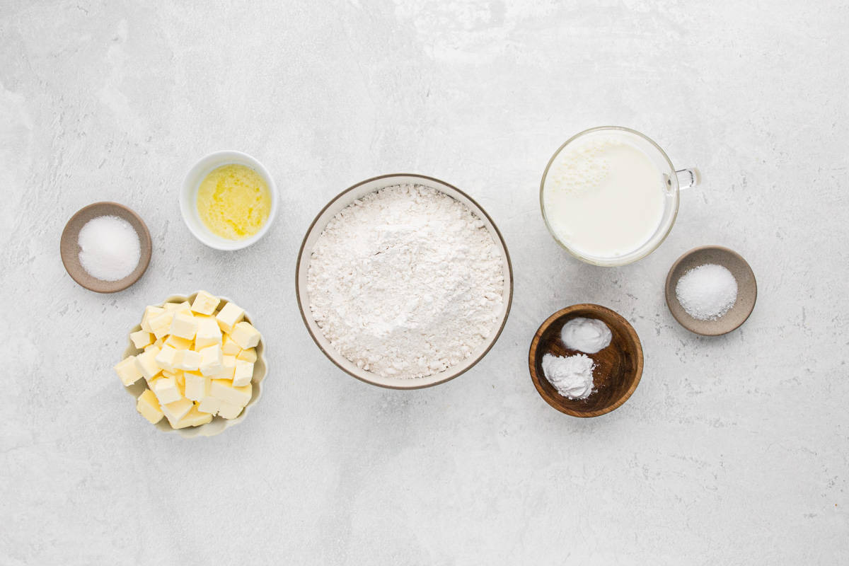 Overhead shot of the ingredients to make cathead biscuits on a white surface