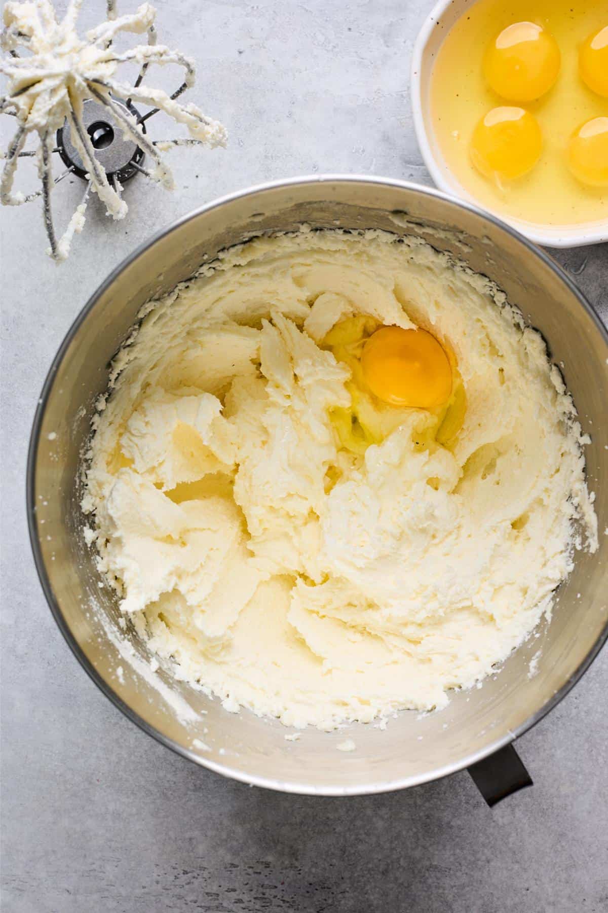 Creamed butter and sugar mixture with a single egg added, mixer whisk attachment nearby