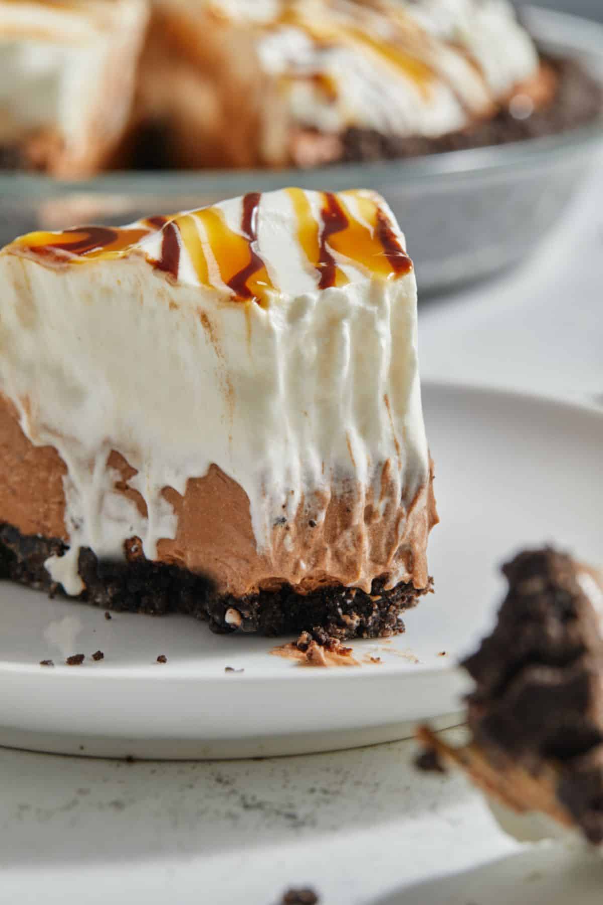 Close up of a slice of chocolate mousse pie on a white plate with a forkful taken out