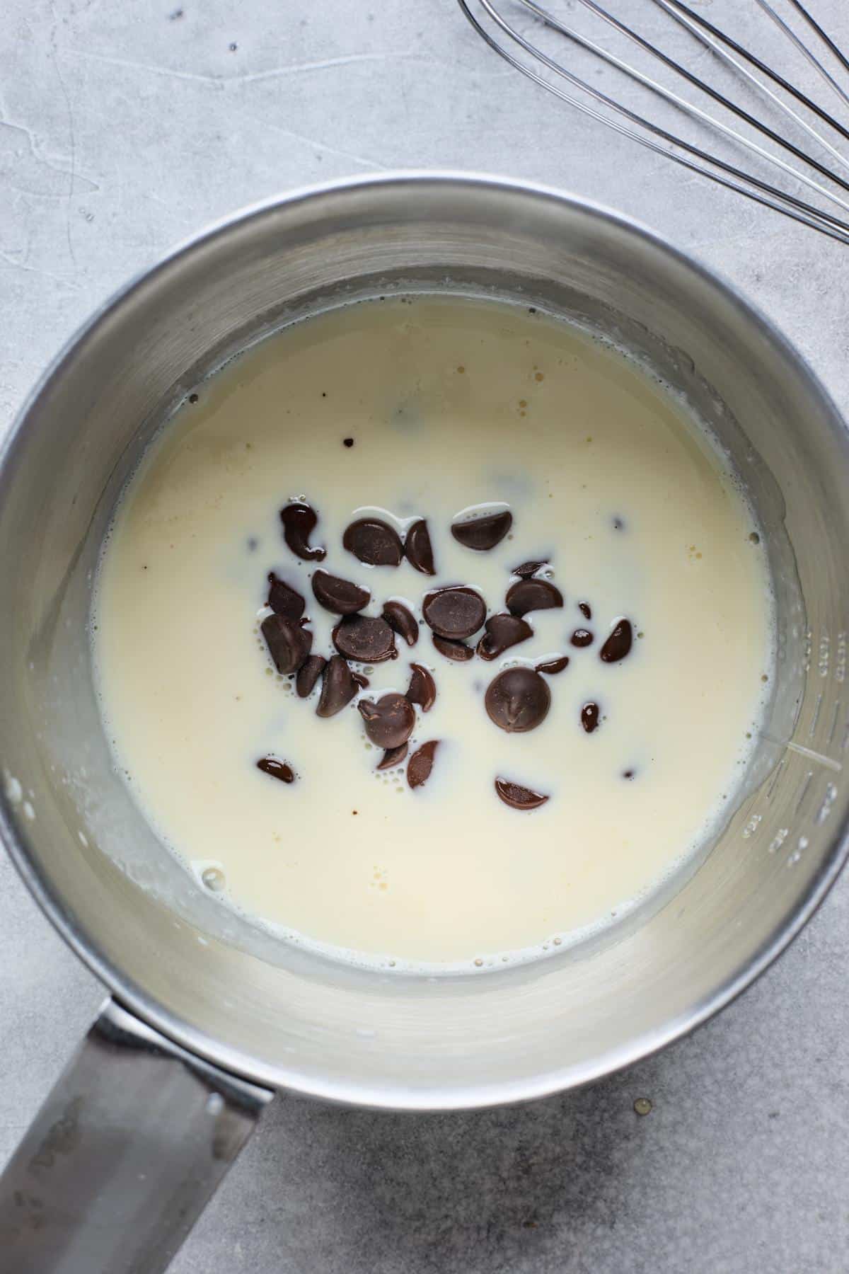 A saucepan with cream and dark chocolate chips added