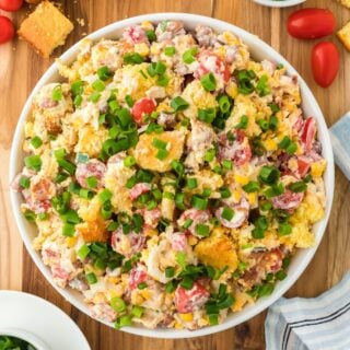 Overhead shot of cornbread salad garnished with green onions in a large white bowl