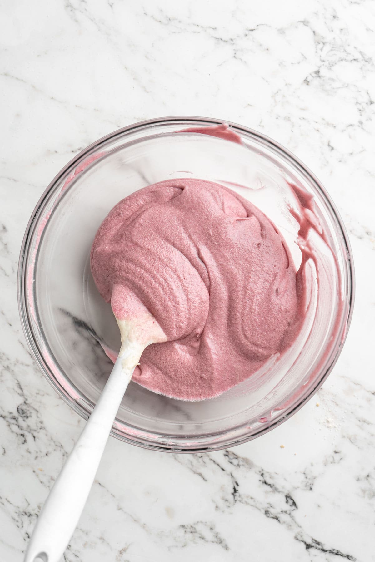 Raspberry cake batter on glass bowl on white countertop