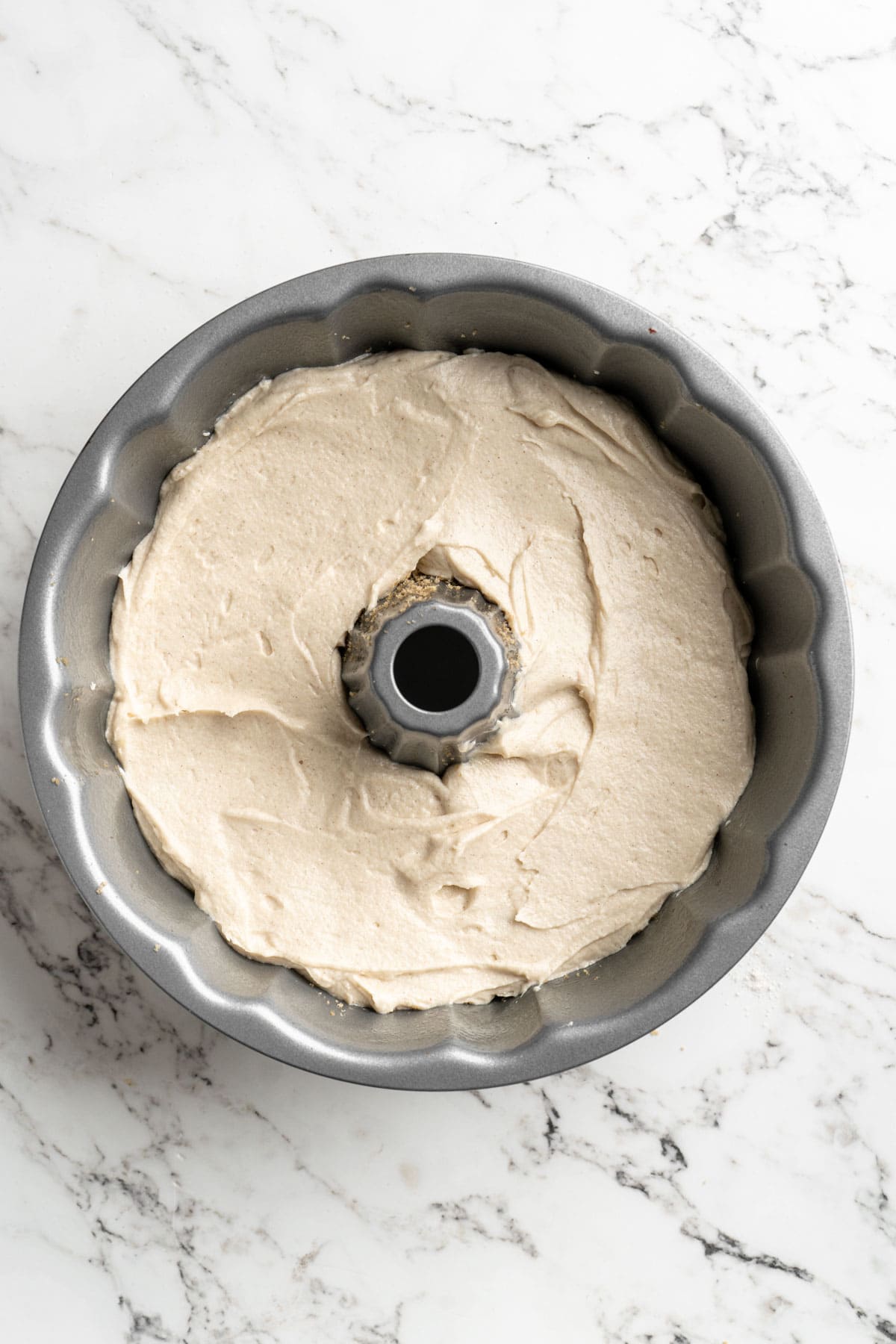 Vanilla cake batter in the bottom of a bundt pan on white countertop