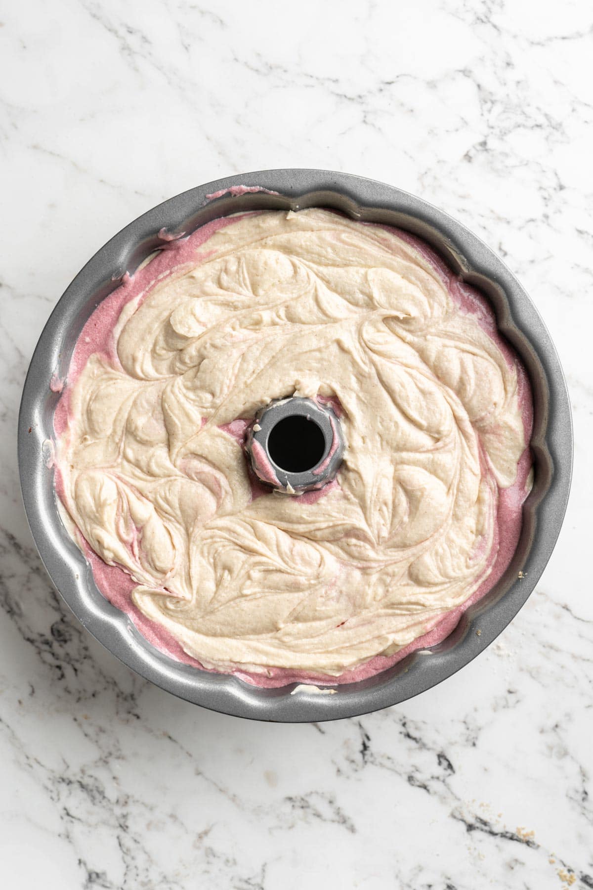 Cranberry bundt batter in a bundt pan before baking on white countertop