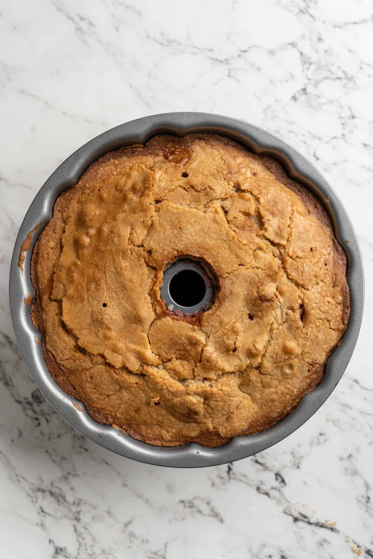 Baked cranberry pound cake in a bundt pan on white countertop before flipping out