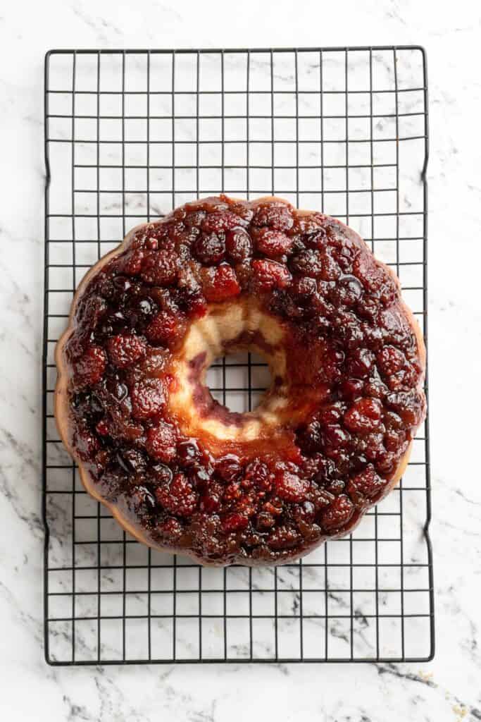 Flipped cranberry upside down cake on wire rack on white countertop