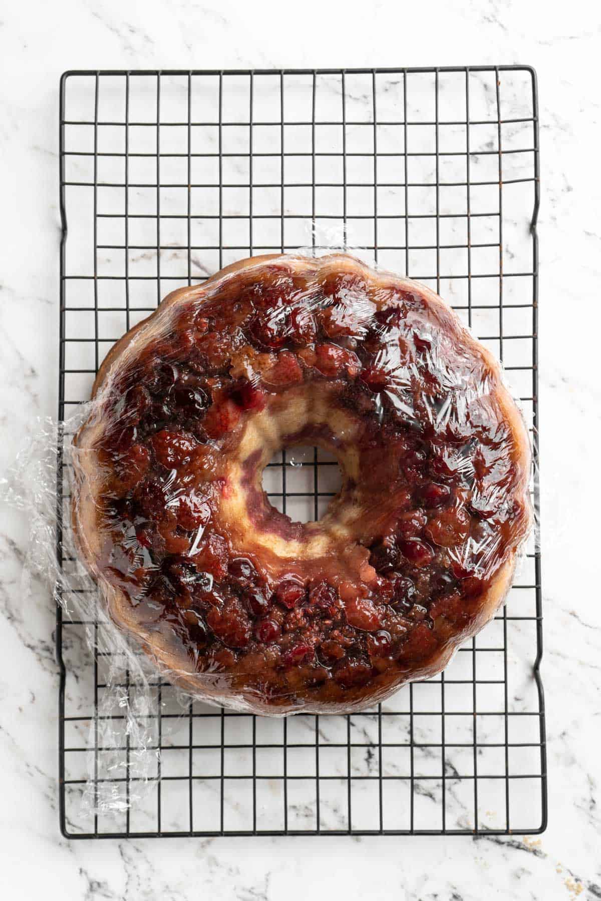 A wrapped cranberry bundt cake recipe on a wire rack