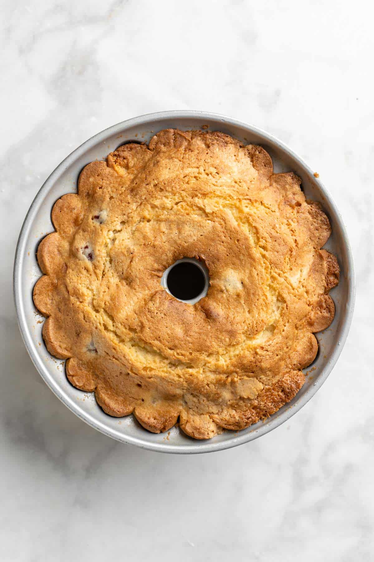 Baked cranberry orange cake in a bundt pan on a white countertop