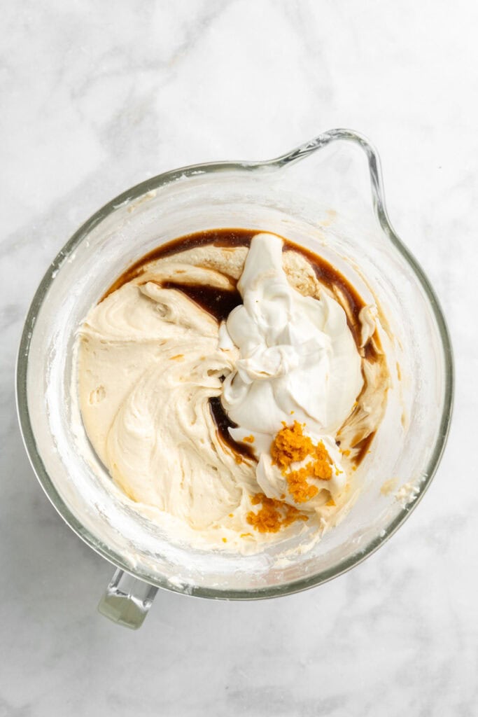 Sour cream and vanilla added to a bundt cake batter in stand mixing bowl