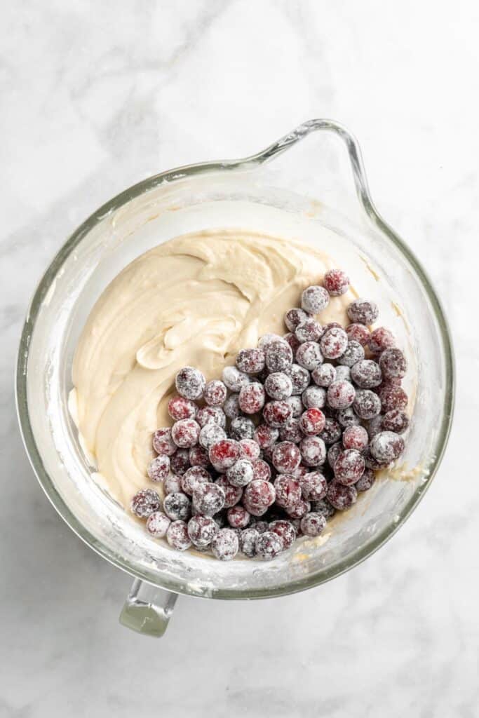 Cranberries added to a cake batter in a mixing bowl
