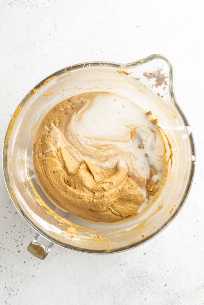 A mixing bowl with the gingerbread batter partially mixed with a swirl of milk added