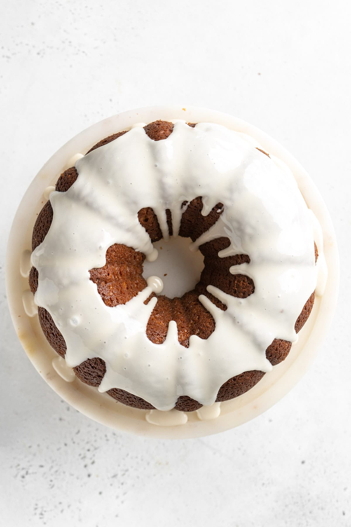 A freshly baked gingerbread cake covered with a white icing drizzle on a plate