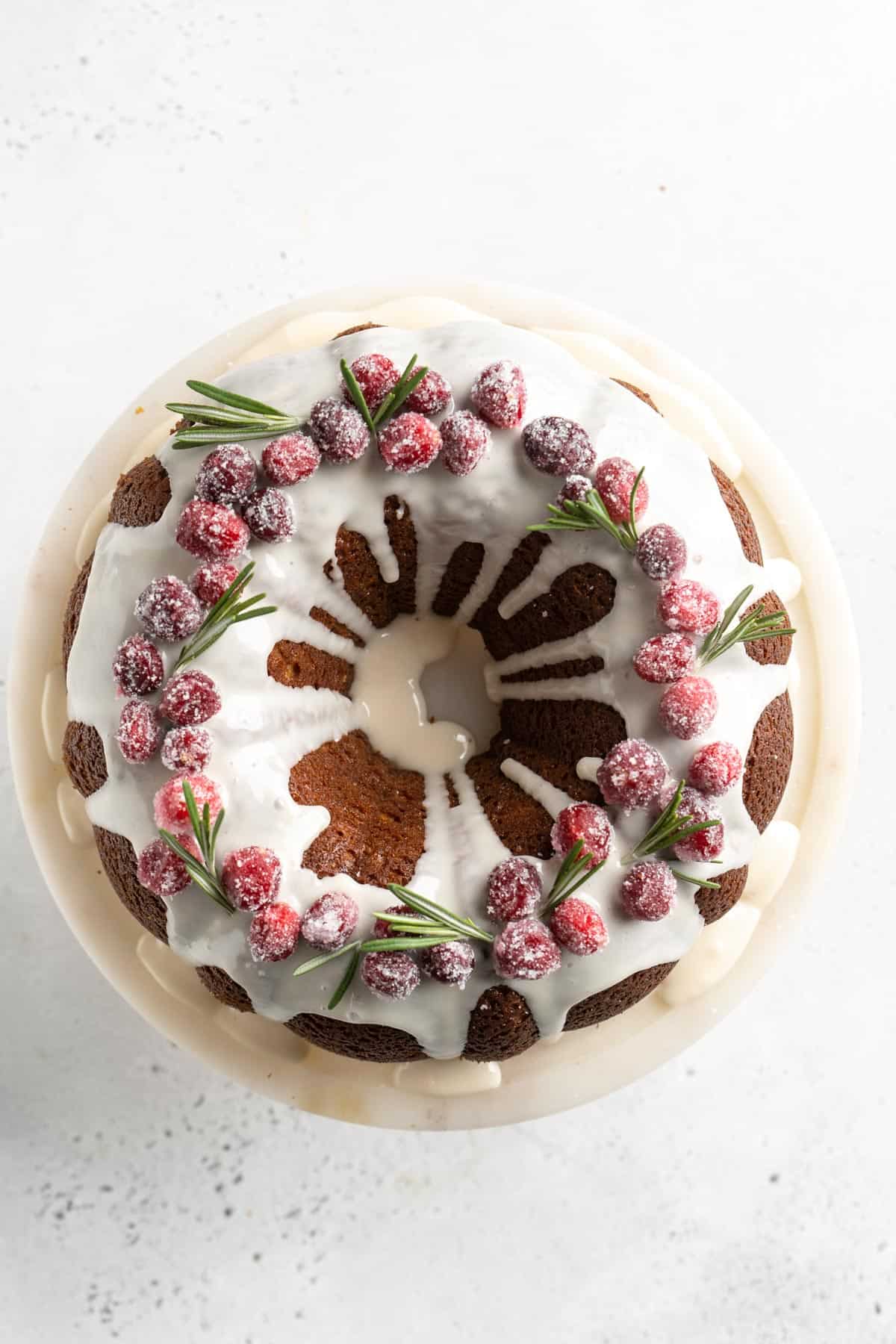 The finished gingerbread cake garnished with sugared cranberries and sprigs of rosemary