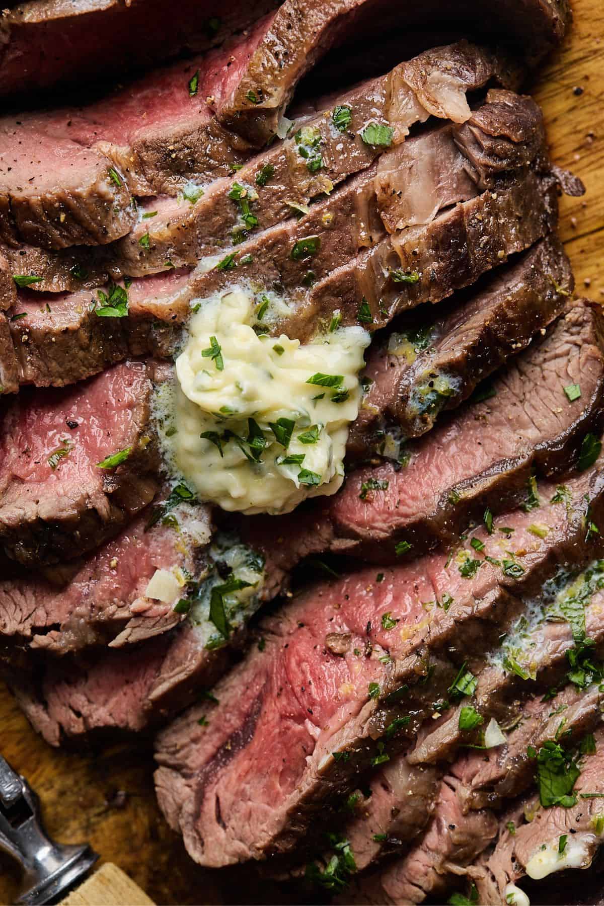 Close up of juicy london broil sliced and smothered with herb butter