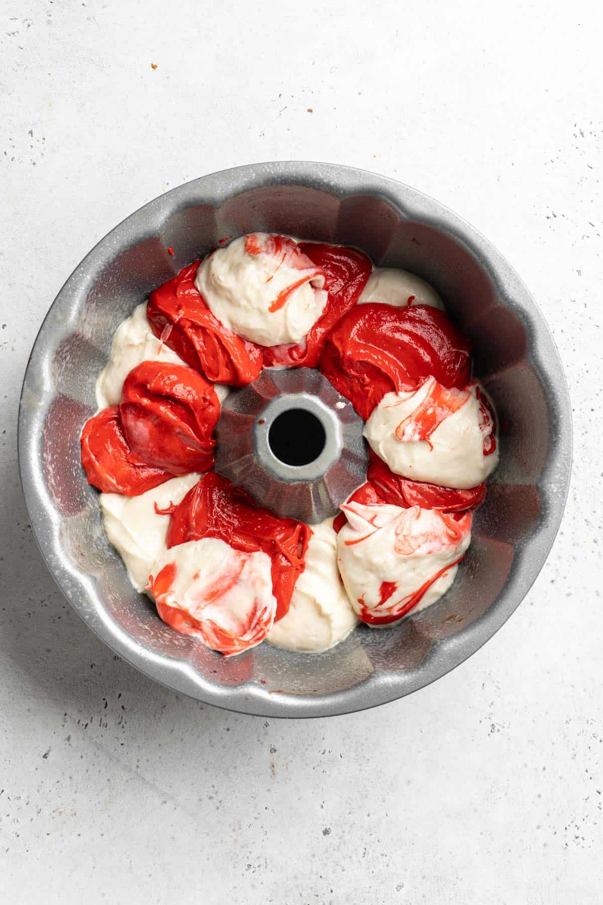 Dollops of red velvet and vanilla cake batter in a bundt pan