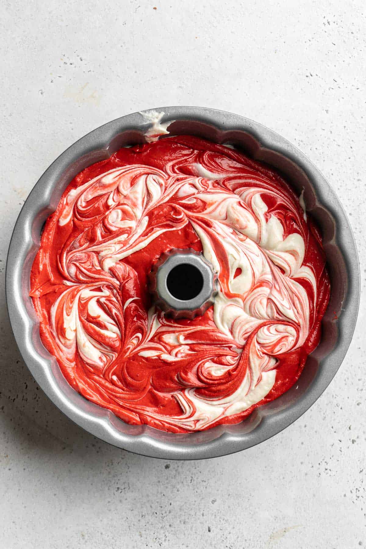 Swirled red velvet marble cake batter in a bundt pan before baking