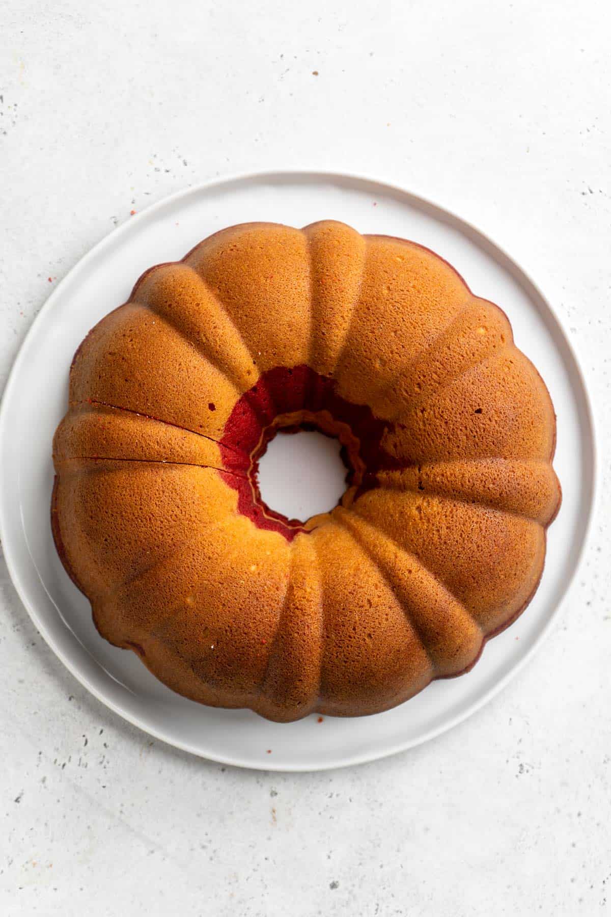 Baked red velvet marble bundt cake out of the oven on white plate on white countertop