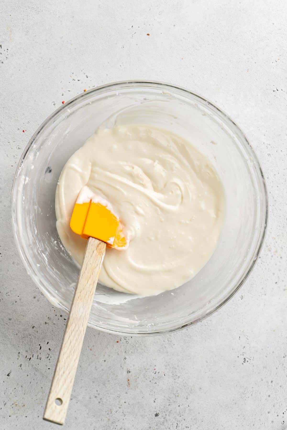 Mixed cream cheese icing with spatula until smooth in glass bowl