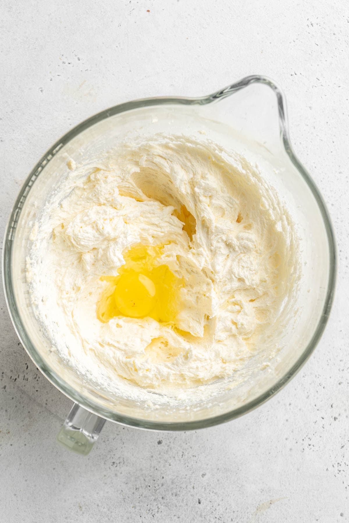 Eggs being added to cake batter in glass bowl