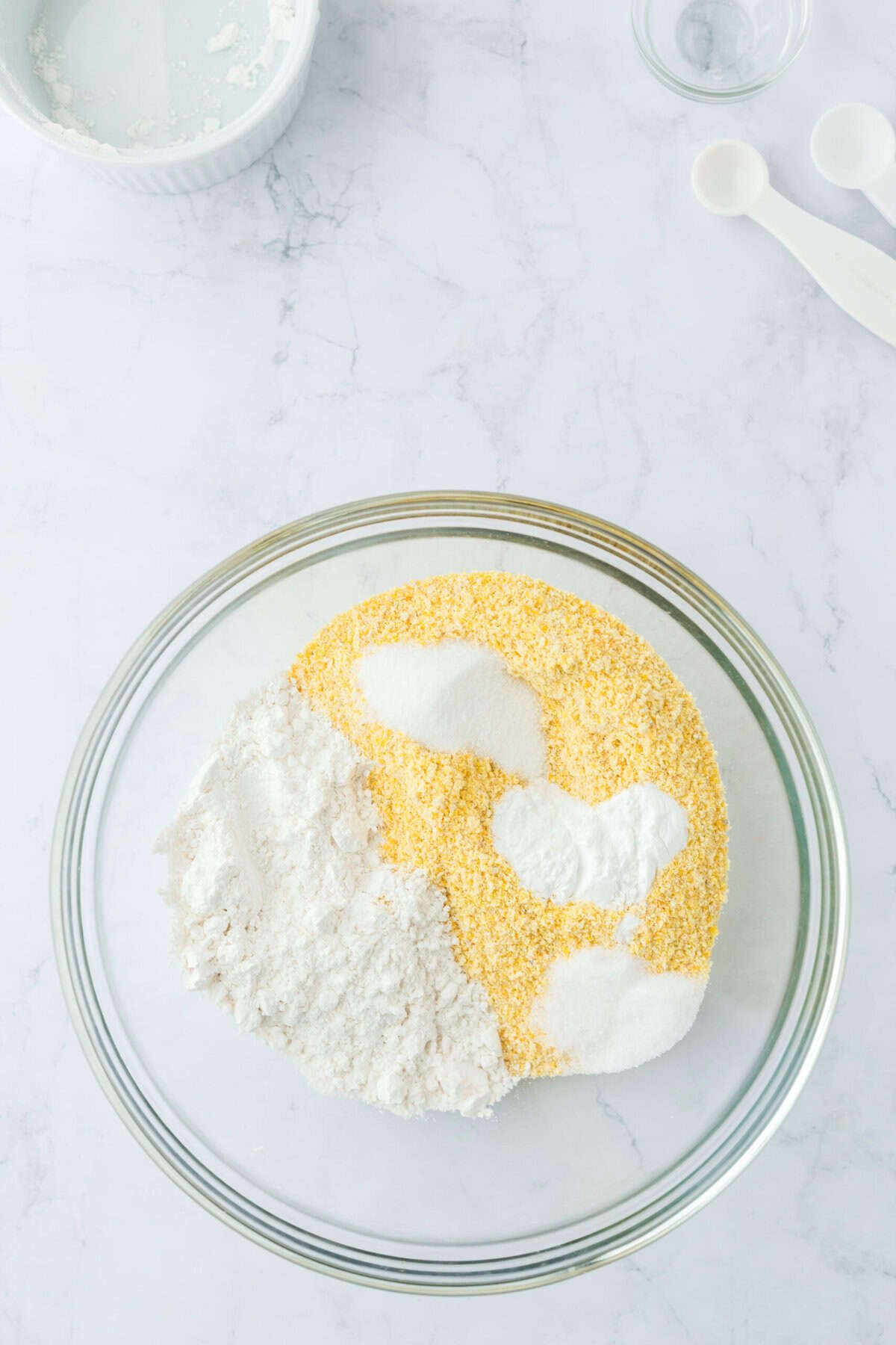 Cornmeal dry ingredients in a glass bowl on white countertop