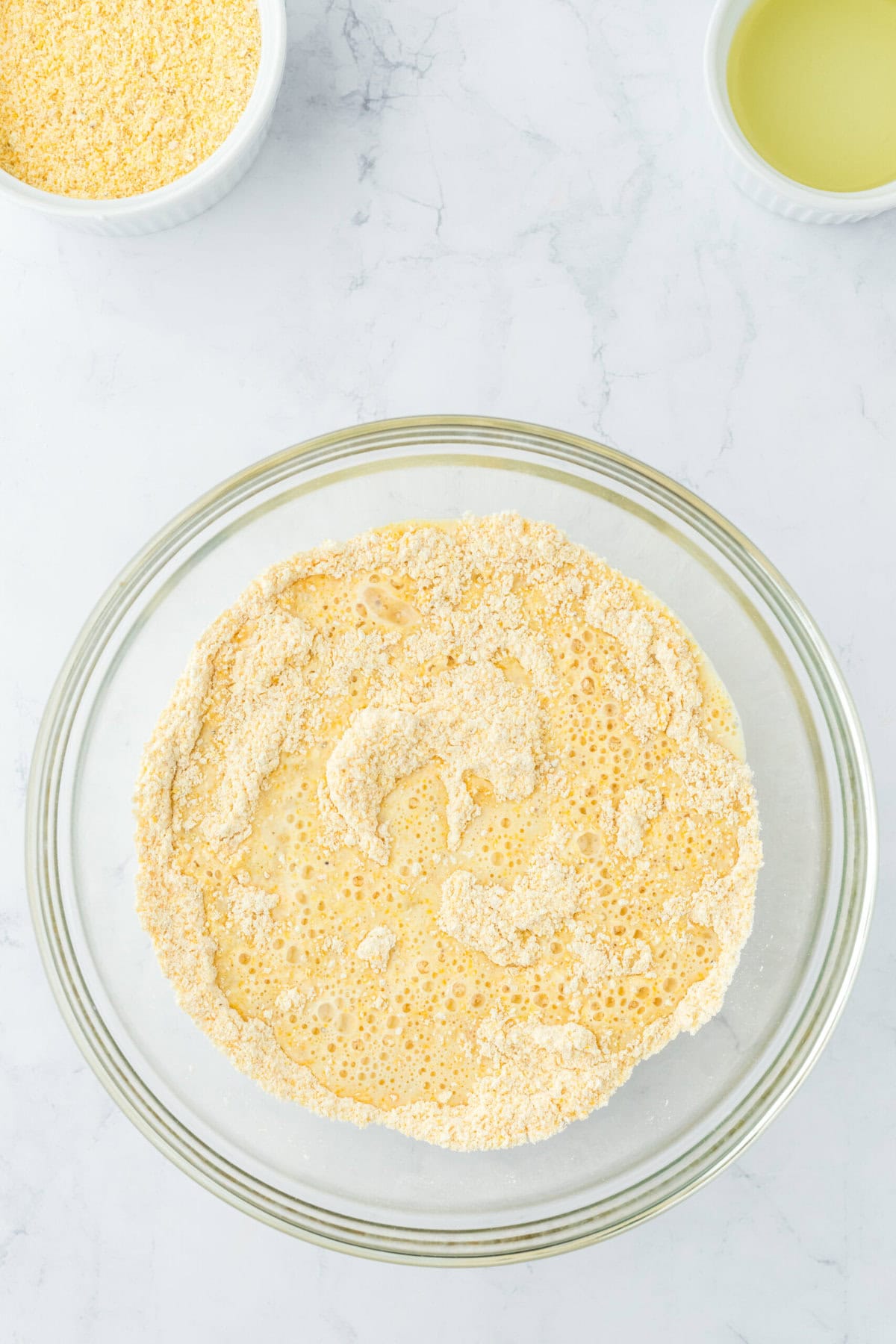 Fried cornbread batter combined in the glass bowl on white countertop